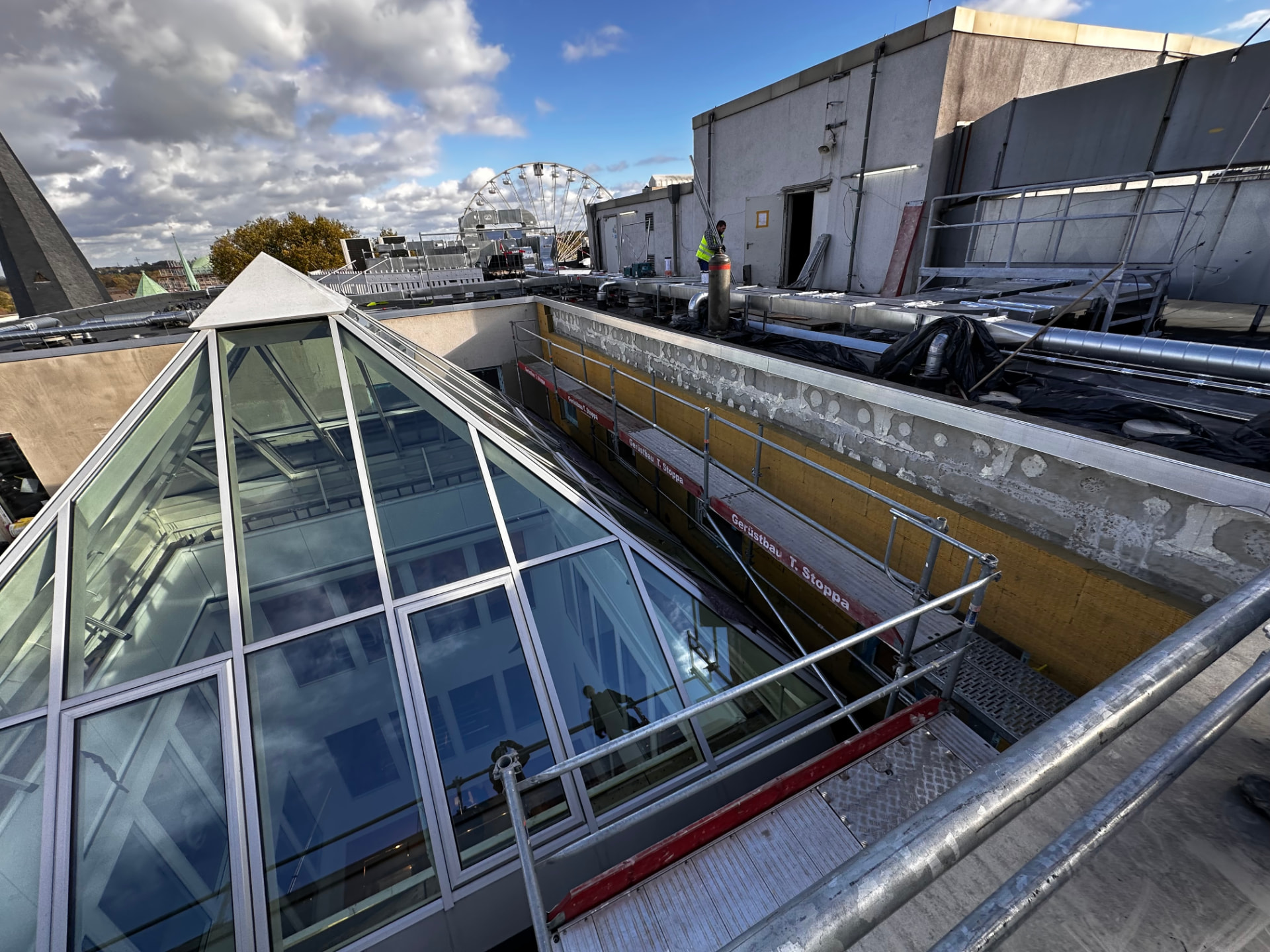 Dachterrasse am Bauvorhaben Peek & Cloppenburg in Essen: Gerüst mit Stoppa-Brettern zur Wandsanierung neben einer verglasten Dachpyramide