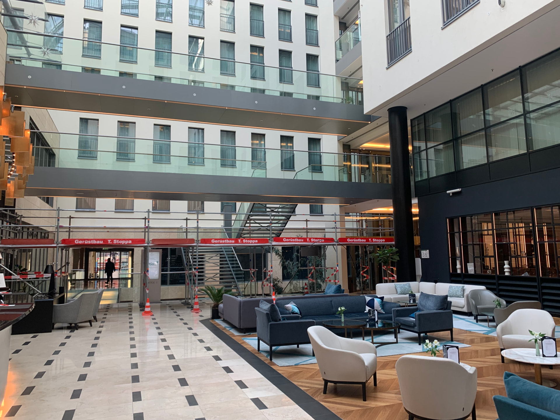 Atrium des Hotels Kö59 in Düsseldorf mit Innengerüst von Gerüstbau Stoppa und roten Stoppa-Gerüstbrettern, Hotellobby im Vordergrund
