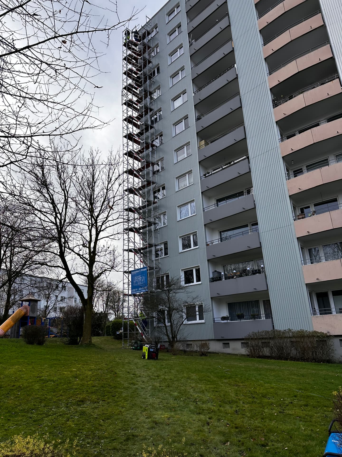 Hochhaus in Velbert mit hochgeführttem Treppenturm-Gerüst von Gerüstbau Stoppa, blaues Stoppa-Banner am Gerüst