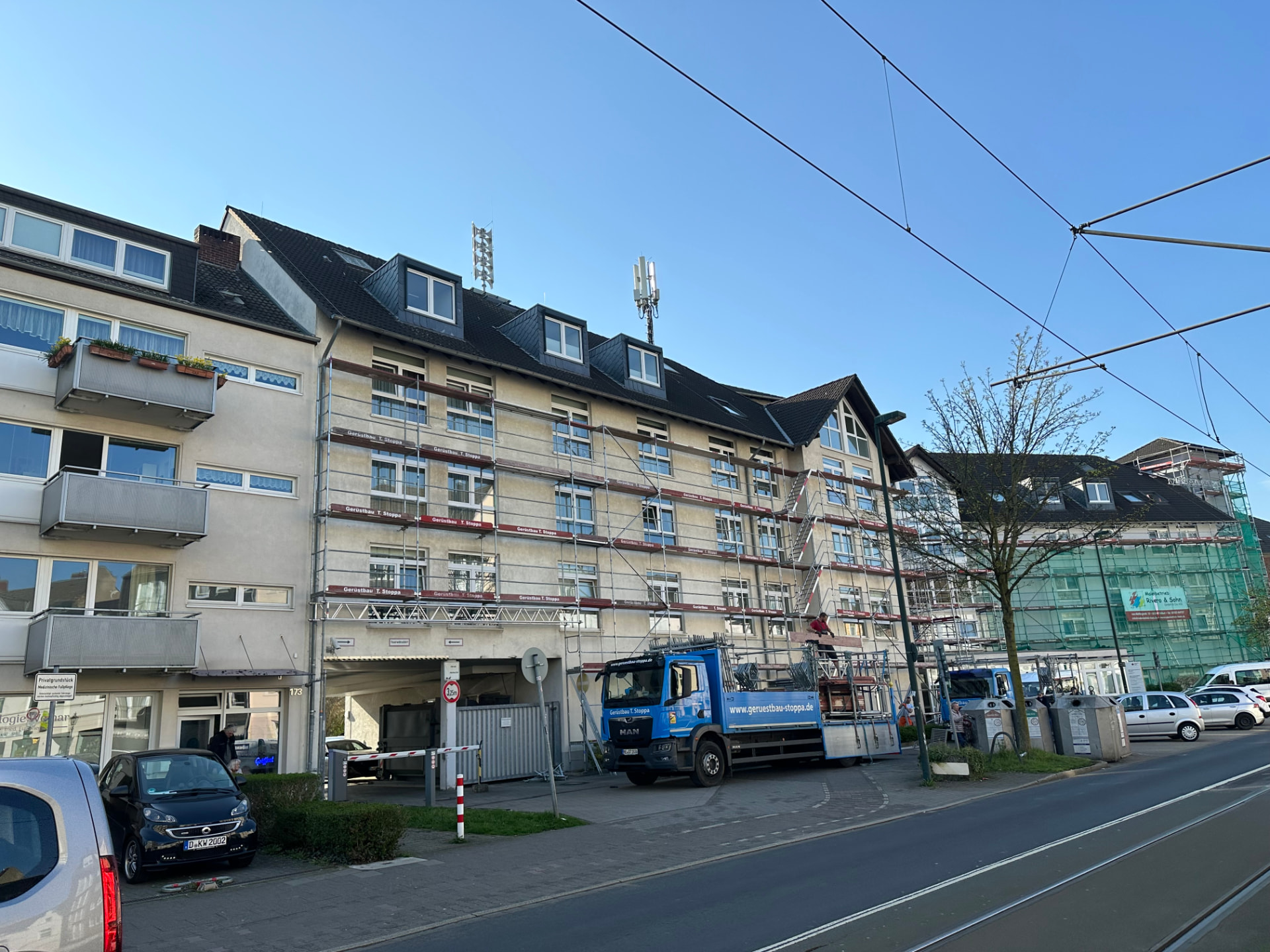 Mehrgeschossiges DRK-Gebäude in Düsseldorf mit vollflächigem Fassadengerüst von Gerüstbau Stoppa, blauer Stoppa-Lkw davor