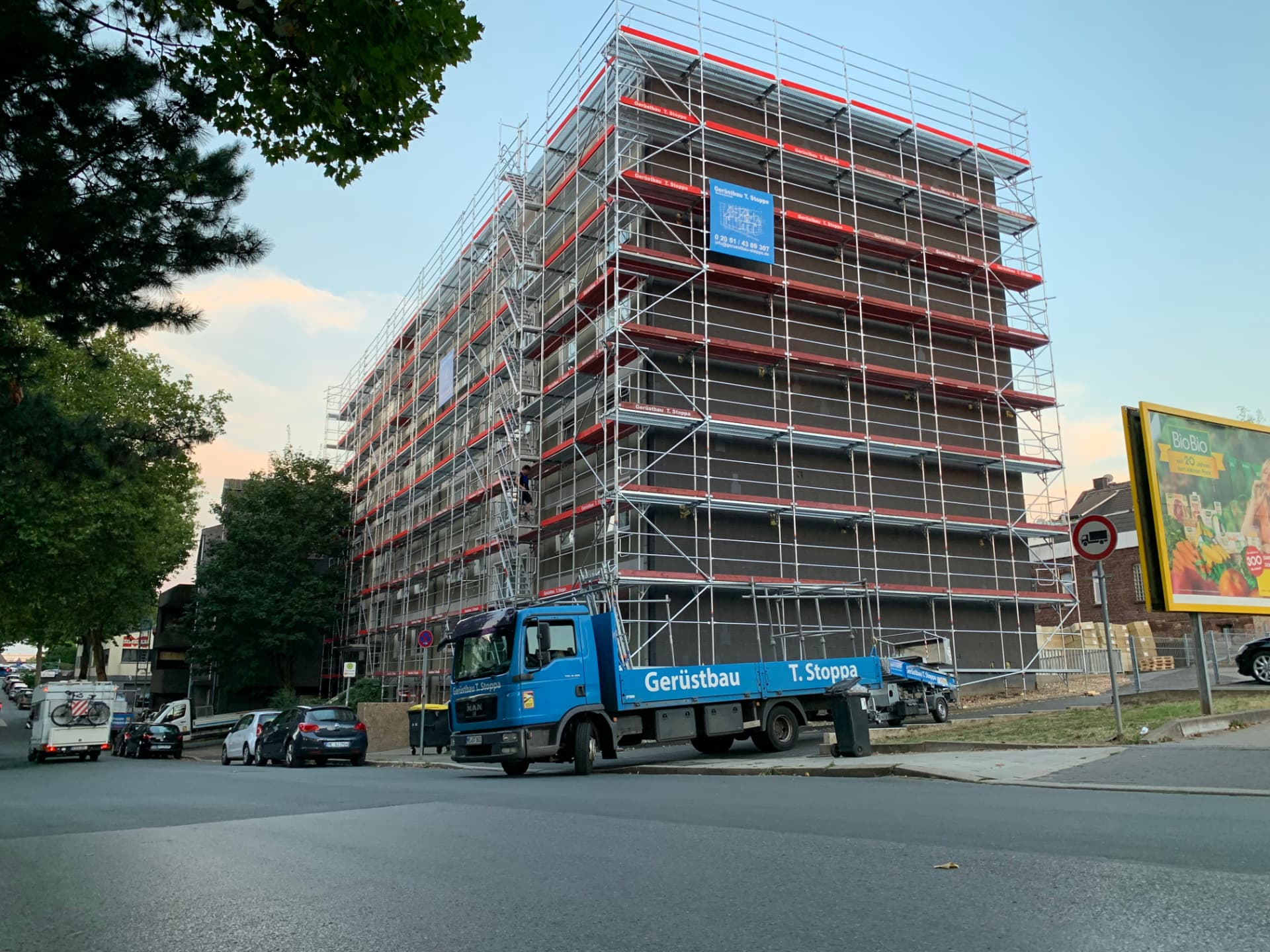 Fassadengerüst an einem mehrgeschossigen Wohngebäude mit blauem Gerüstbau-Stoppa-Lkw im Vordergrund