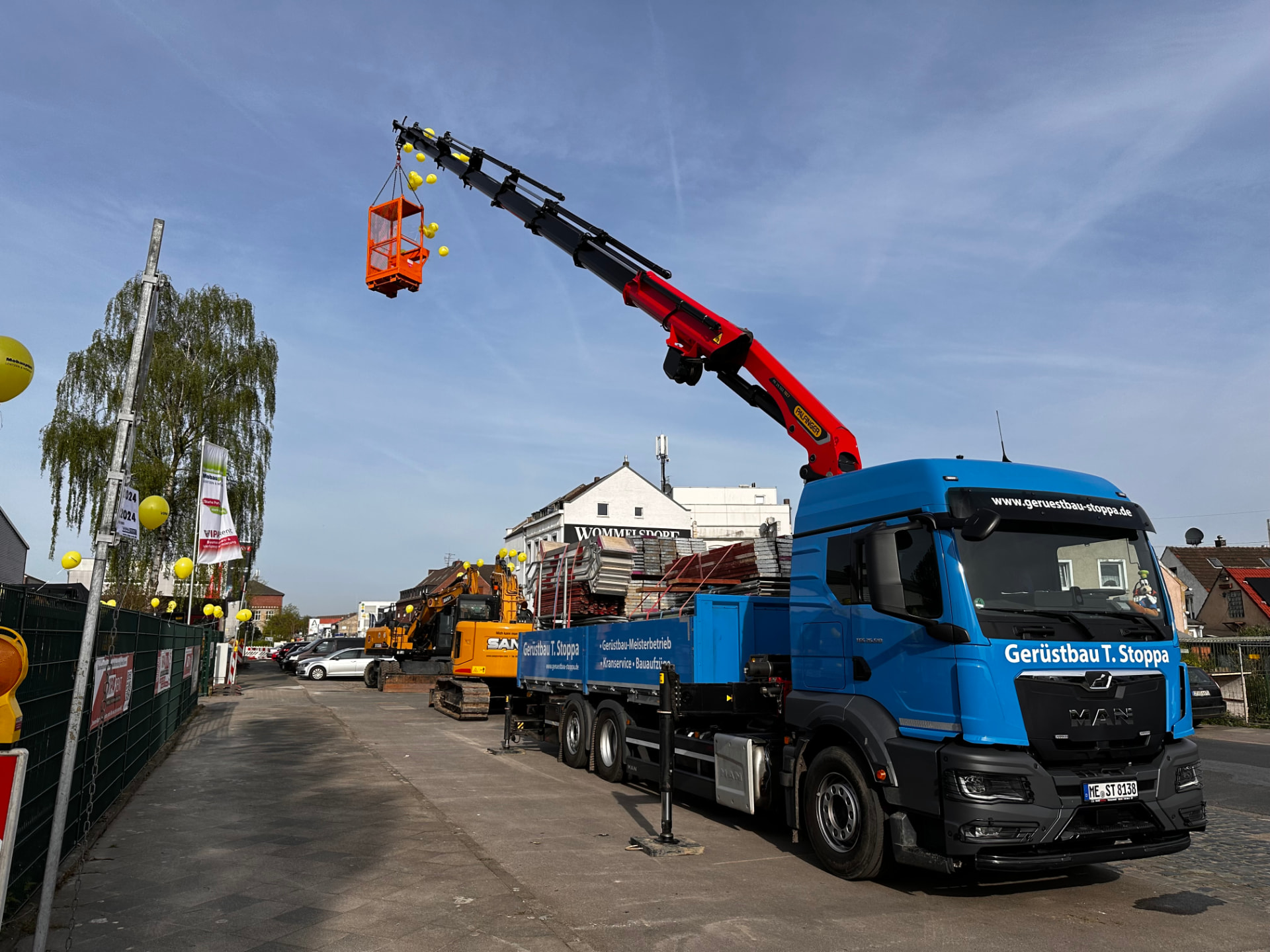 Blauer Gerüstbau-Stoppa-Lkw mit Ladekran und voll beladener Ladefläche auf einer Baustelle