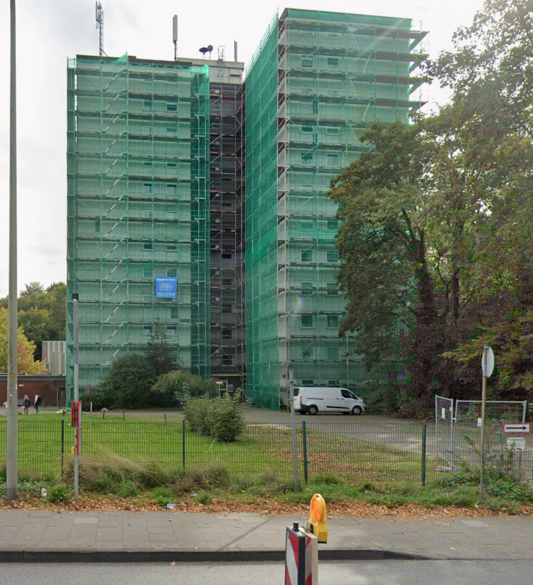 Zwei Wohnhochhäuser in Wülfrath mit vollflächigem Fassadengerüst und grünen Schutznetzen von Gerüstbau Stoppa, blaues Stoppa-Banner am Gerüst