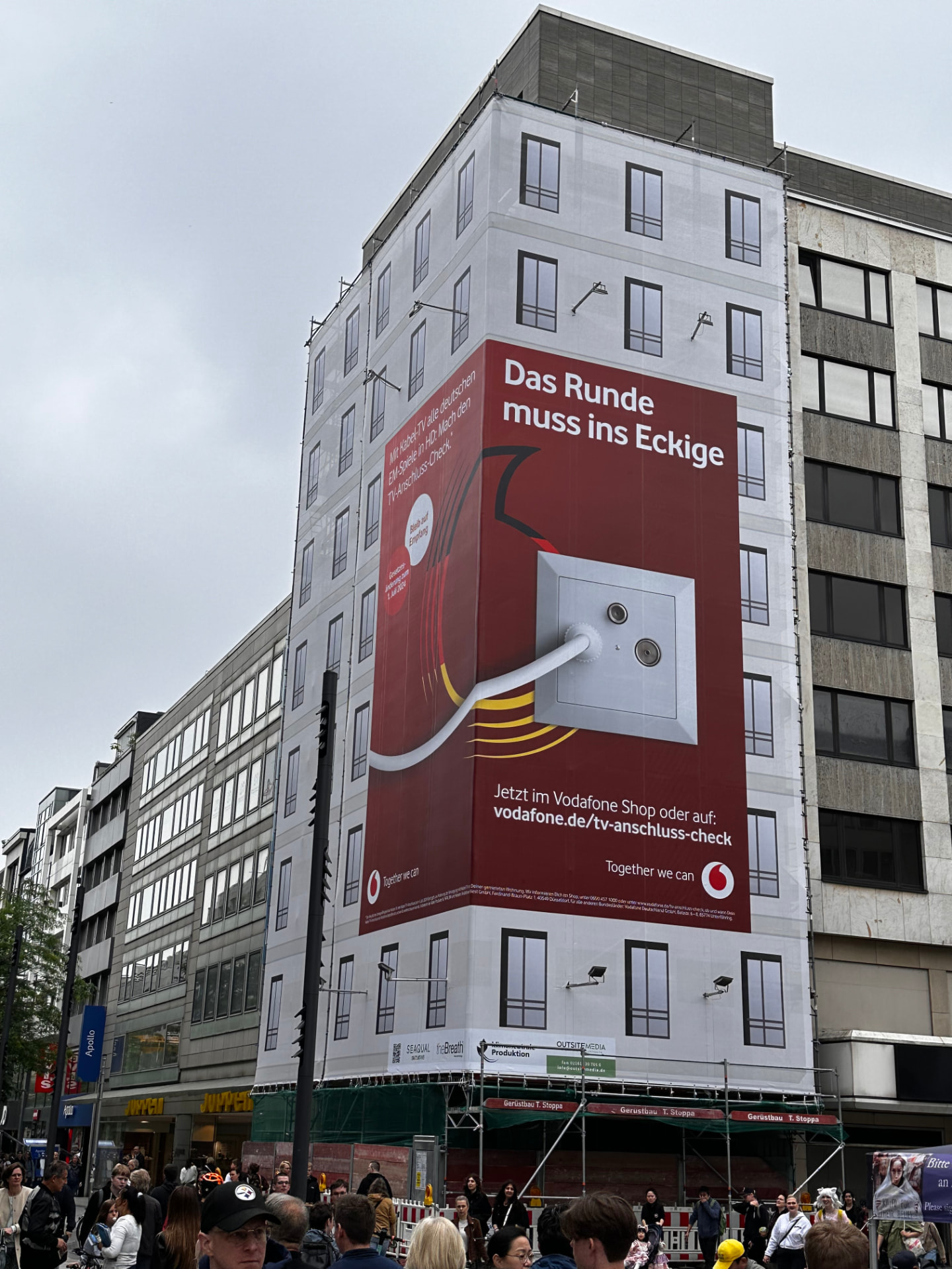 Eckgebäude in der Düsseldorfer Innenstadt mit Werbegerüst und bedruckten Werbebanderolen, unten Stoppa-Gerüstbretter und Absperrungen